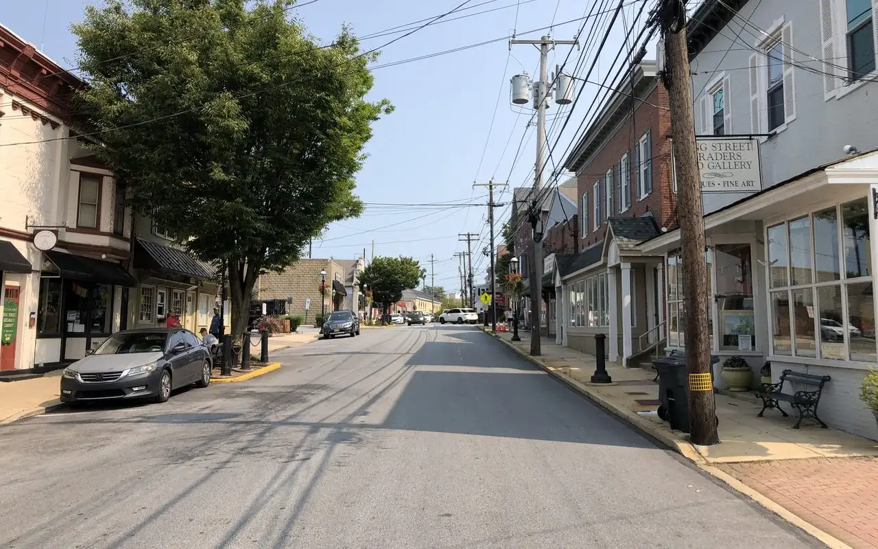 King Street in Malvern on a summer day, lined with older brick and painted storefronts under shade trees