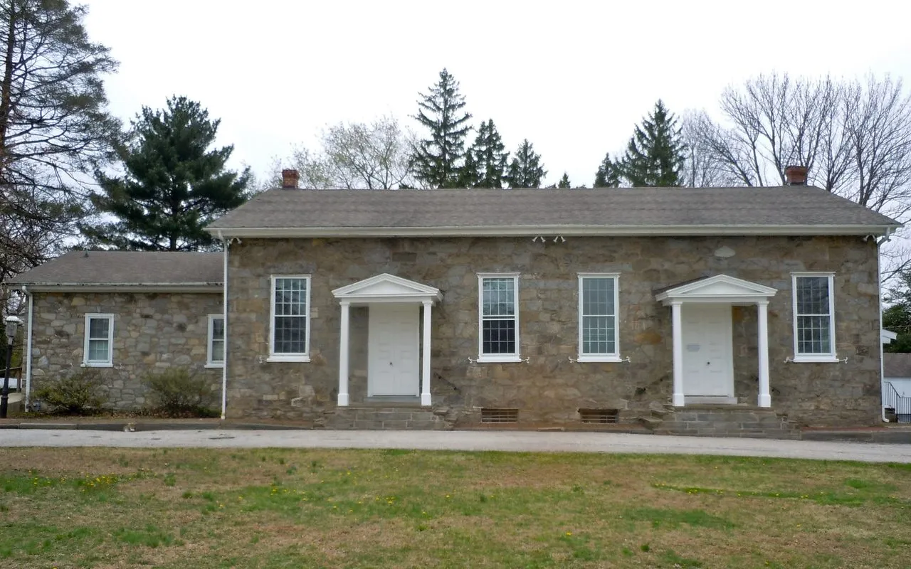 The Springfield Friends Meeting House, a long fieldstone meetinghouse with two white columned doorways, set back on a lawn